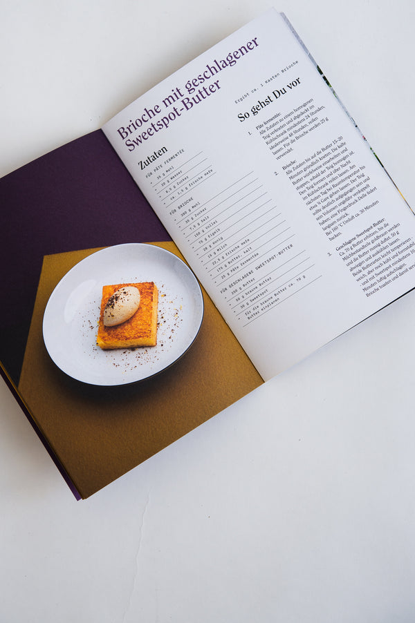 Aufgeschlagenes Rezeptheft mit Brioche und geschlagener Sweet-Spot-Butter.
